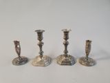 three silver candlesticks are sitting on a white surface