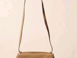 un sac à main beige posé sur une table près d'un mur blanc