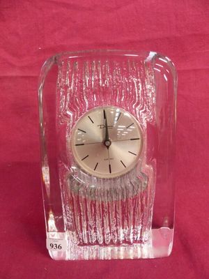 a clear glass clock with a black face on a red background
