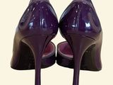 pair of purple high heeled shoes sitting on top of a white surface
