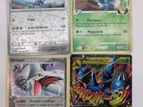 quatre cartes Pokémon différentes sont posées sur une surface blanche