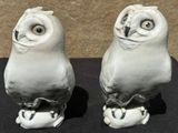 two white owl figurines sitting on a black table