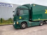 a green semi truck parked in front of a building