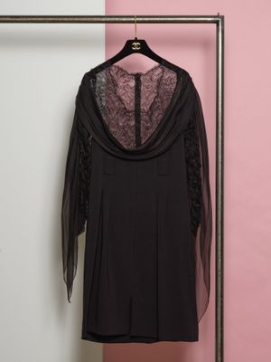 une robe noire suspendue à un cintre devant un mur rose