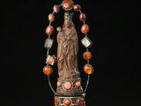 une statue représentant une femme tenant un chapelet et entourée de perles orange