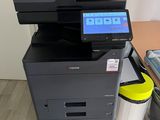 a printer sitting on top of a desk next to a trash can
