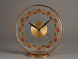 une horloge dorée ornée de perles rouges, posée sur une table