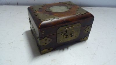 une petite boîte en bois posée sur une table, sur laquelle se trouve une horloge