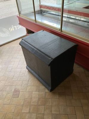 une boîte noire posée par terre devant une vitrine