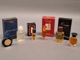 five different perfumes in a row on a white surface