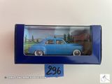 une petite voiture bleue dans une boîte bleue posée sur une surface blanche