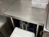 a trash can sitting in the corner of a stainless steel kitchen