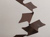 a metal sculpture of a piece of paper flying in the air