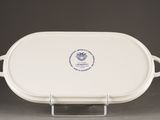 an oval serving dish with handles and a blue emblem on the side