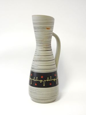 un vase blanc orné de motifs noirs et rouges