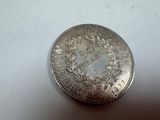 an old silver coin sitting on top of a white surface