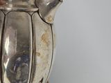 a person holding a silver tea pot in their hand