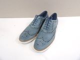 une paire de chaussures bleues posée sur une table blanche, avec un mur en arrière-plan