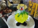 une figurine en verre représentant un clown, posée sur une assiette