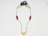 un gros plan d'un collier posé sur une surface blanche, muni d'un cordon noir
