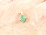 a close up of a person ' s hand holding a ring with a green stone