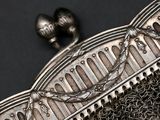a silver purse with a chain around it on a black surface