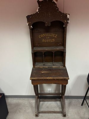 an old wooden desk with a sign on it in a room