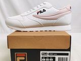 des chaussures Fila dans une boîte posée sur une table, sur fond blanc