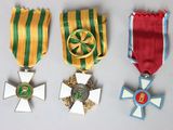 three medals and a cross on a white surface