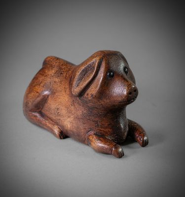 wooden sculpture of a pig laying down on a gray surface