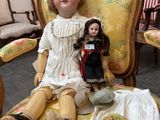 a doll that is sitting on a chair with a doll