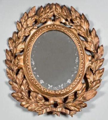 un miroir avec un cadre doré orné d'un motif de feuilles