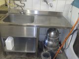 un évier en inox dans une cuisine, à côté d'un seau