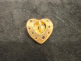 a gold heart shaped brooch on a black surface