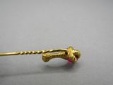 an image of a gold stick with a pink bead on it