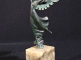 une statue en bronze représentant une femme ailée, posée sur un socle en marbre