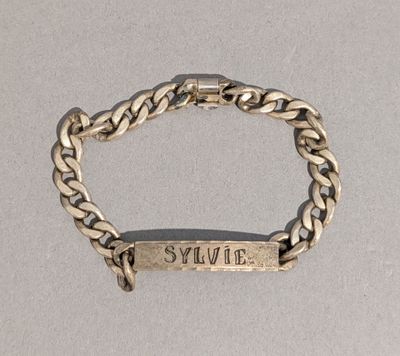 un gros plan sur un bracelet en argent sur lequel figure un prénom
