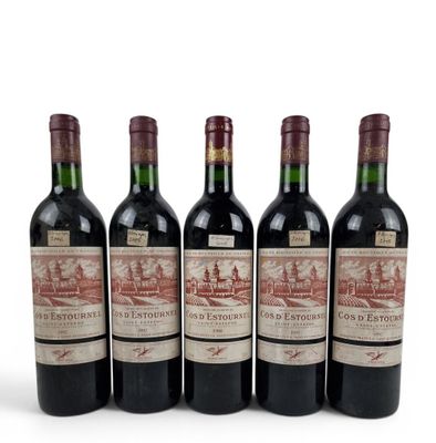 four bottles of red wine are lined up on a white surface