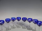 twelve blue wine glasses lined up in a circle on a white surface