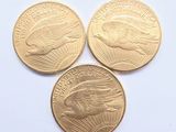 Trois pièces d'or sont représentées sur une surface blanche