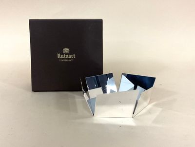 une boîte contenant un objet argenté, posée sur une surface blanche