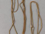 two gold necklaces with a gold chain on a white surface