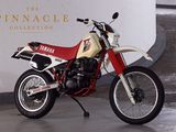 une moto rouge et blanche garée devant l'enseigne « Pinnacle Collection »