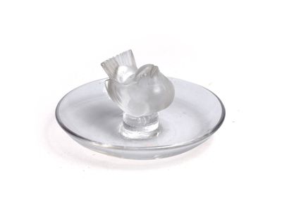 une plaque de verre sur laquelle est posé un oiseau en verre