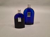 two blue glass bottles with silver caps are sitting on a white surface