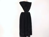 a black dress on a mannequin stand with a white background