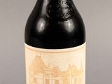 une bouteille de vin rouge sur un fond gris, avec un bâtiment en arrière-plan