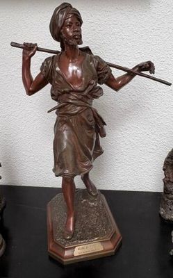 une statue représentant une femme tenant un bâton, posée sur une table