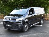 une camionnette noire garée sur un parking, avec des arbres en arrière-plan