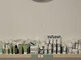many toothbrushes lined up on a shelf with a clock on the wall